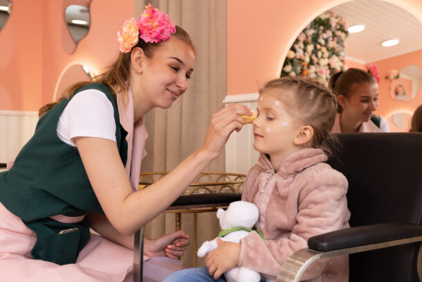 The woman is doing a face painting for the child.